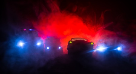 Police car chasing a car at night with fog background. 911 Emergency response police car speeding to...