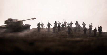 War Concept. Military silhouettes fighting scene on war fog sky background, World War Soldiers Silhouettes below Cloudy Skyline at sunset. Attack scene. Armored vehicles. tank in actionの写真素材