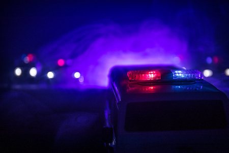 Police cars at night. Police car chasing a car at night with fog background. 911 Emergency response police car speeding to scene of crime. Selective focusの写真素材