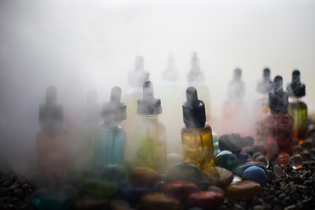 Vape concept. Beautiful colorful vape liquid glass bottles outdoor on stones. Useful as background...
