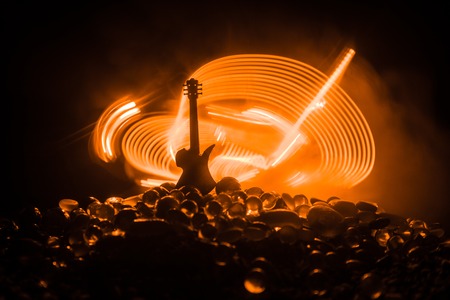 Music concept. Acoustic guitar on a dark background under beam of light with smoke. Emptry space for text. Fire effects. Surreal guitarの写真素材