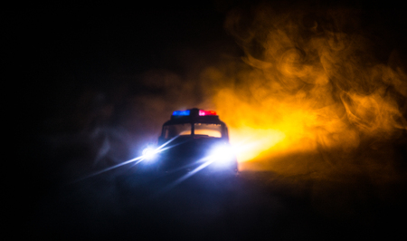 Police cars at night. Police car chasing a car at night with fog background. 911 Emergency response police car speeding to scene of crime. Selective focusの写真素材