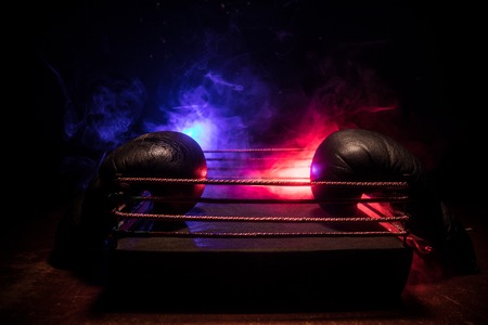 Empty boxing ring with red ropes for match in the stadium arena. Boxing gloves ready to fight. Empty space for text. Foggy background with light. Selective focusの写真素材