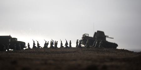 War Concept. Military silhouettes fighting scene on war fog sky background, World War Soldiers Silhouettes below Cloudy Skyline at sunset. Attack scene. Armored vehicles. tank in actionの写真素材