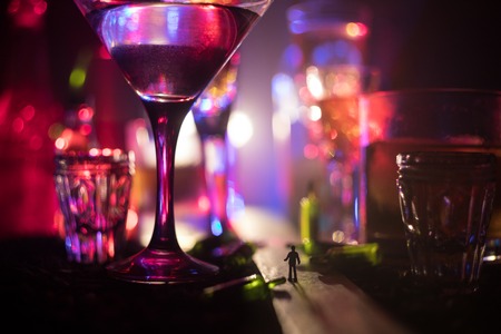 Abstract alcoholism concept. Silhouette of a man standing in the middle of the road on a misty night with giant glasses filled with alcoholic beverage. Creative artwork decorationの写真素材