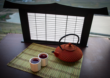 Tea concept. Japanese tea ceremony culture east beverage. Teapot and cups on table with bamboo on sunsetの写真素材