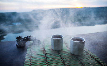 Tea concept. Japanese tea ceremony culture east beverage. Teapot and cups on table with bamboo on sunsetの写真素材