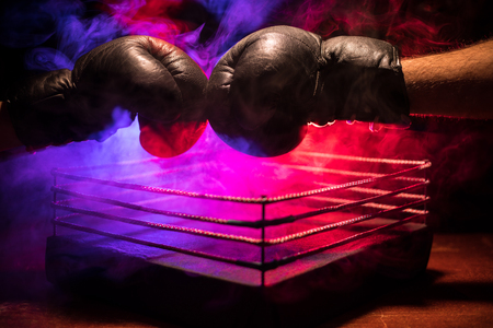 Empty boxing ring with red ropes for match in the stadium arena. Boxing gloves ready to fight. Empty space for text. Foggy background with light. Selective focusの写真素材