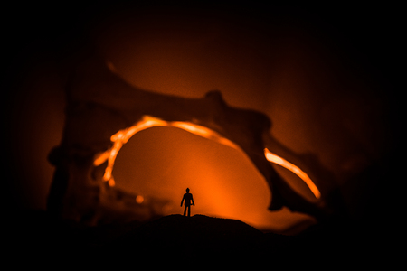 Artwork decoration with animal bone. Silhouette in an underground abandoned crypt. man standing in front of a cave entrance. Selective focusの写真素材
