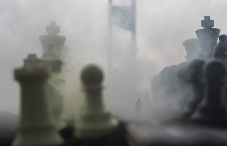 Chess concept of business and strategy ideas. Silhouette of a man standing in the middle of the road with giant chess figures and Guillotine. Artwork decoration. Selective focusの写真素材