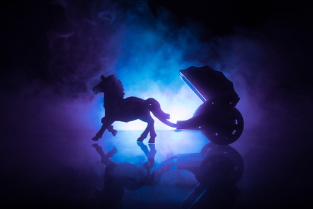 Artwork decoration. Silhouette of old coach with horse on dark toned foggy background. Selective focusの写真素材