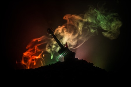 Music concept. Acoustic guitar on a dark background under beam of light with smoke. Emptry space for text. Fire effects. Surreal guitarの写真素材