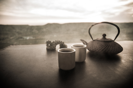 Tea concept. Japanese tea ceremony culture east beverage. Teapot and cups on table with bamboo on sunsetの写真素材