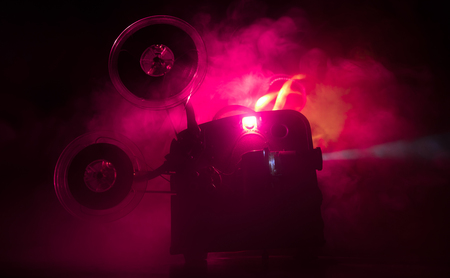 Old vintage movie projector on a dark background with fog and light. Concept of film-making. Selective focusの写真素材