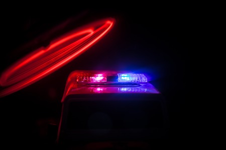 Police cars at night. Police car chasing a car at night with fog background. 911 Emergency response police car speeding to scene of crime. Selective focusの写真素材