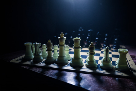 Chess board game concept of business ideas and competition. Chess figures on a dark background with smoke and fog. Selective focusの写真素材