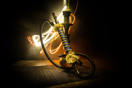 Hookah hot coals on shisha bowl on dark foggy background. Stylish oriental shisha. Creative concept