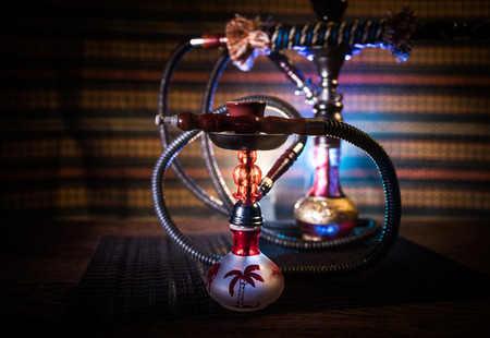 Hookah hot coals on shisha bowl on dark foggy background. Stylish oriental shisha. Creative concept