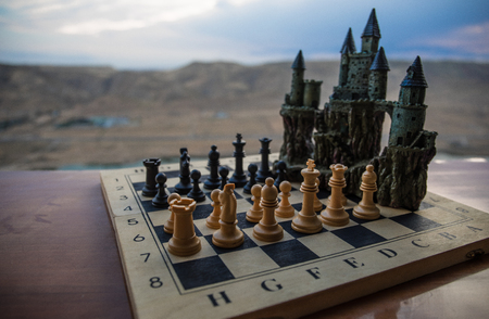 Chess board game concept of business ideas and competition. Chess figures and old medieval castle on a chessboard. Outdoor sunset background. Selective focusの写真素材