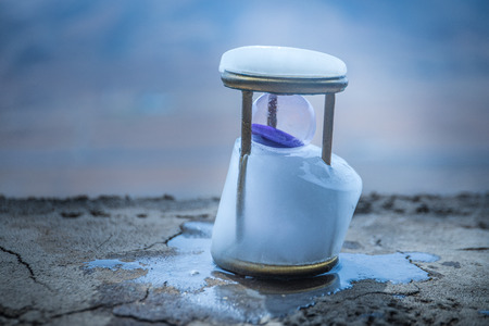 A concept of frozen time. Hourglass in ice. Creative artwork decoration. Selective focus