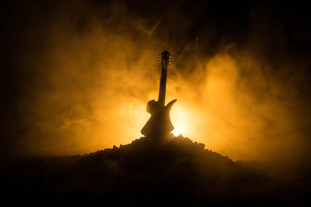 Music concept. Acoustic guitar on a dark background under beam of light with smoke. Emptry space for text. Fire effects. Surreal guitarの写真素材
