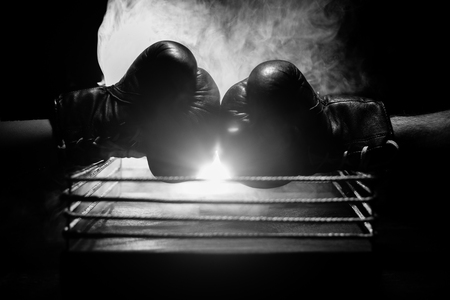 Empty boxing ring with red ropes for match in the stadium arena. Boxing gloves ready to fight. Empty space for text. Foggy background with light. Selective focusの写真素材