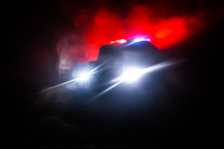 Police cars at night. Police car chasing a car at night with fog background. 911 Emergency response police car speeding to scene of crime. Selective focusの写真素材
