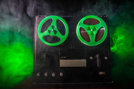 Old vintage reel to reel player and recorder on dark toned foggy background. Analog Stereo Open Reel...