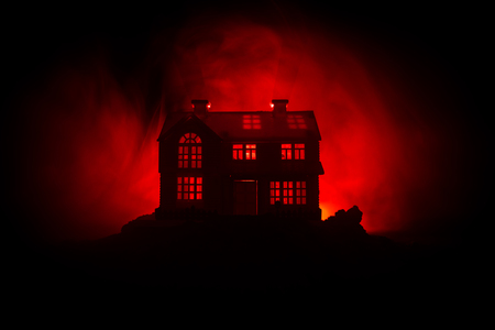 Old house with a Ghost in the forest at night or Abandoned Haunted Horror House in fog. Old mystic building in dead tree forest. Trees at night with moon. Surreal lights. Horror Halloween conceptの写真素材