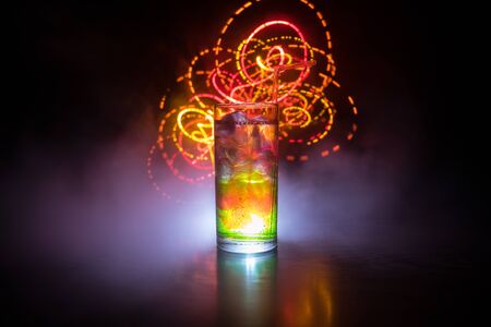 Cocktail glass splashing on dark toned smoky background or colorful cocktail in glass. Party club...