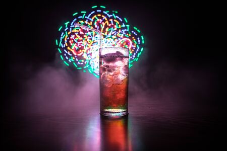 Cocktail glass splashing on dark toned smoky background or colorful cocktail in glass. Party club entertainment. Mixed light. Selective focusの写真素材