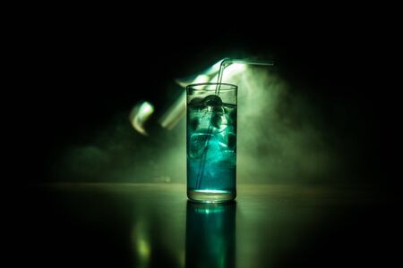 Cocktail glass splashing on dark toned smoky background or colorful cocktail in glass. Party club entertainment. Mixed light. Selective focusの写真素材