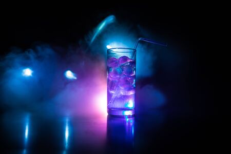 Cocktail glass splashing on dark toned smoky background or colorful cocktail in glass. Party club...
