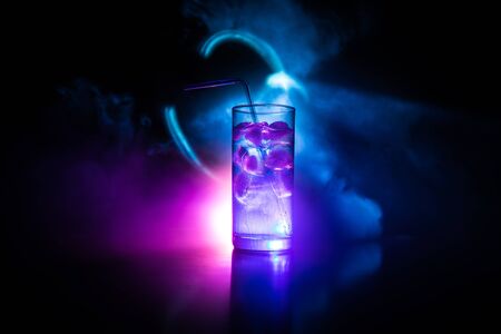 Cocktail glass splashing on dark toned smoky background or colorful cocktail in glass. Party club entertainment. Mixed light. Selective focusの写真素材