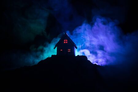 Old house with a Ghost in the forest at night or Abandoned Haunted Horror House in fog. Old mystic building in dead tree forest. Trees at night with moon. Surreal lights. Horror Halloween conceptの写真素材