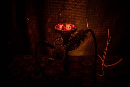 Hookah hot coals on shisha bowl on dark foggy background. Stylish oriental shisha. Creative conceptの写真素材