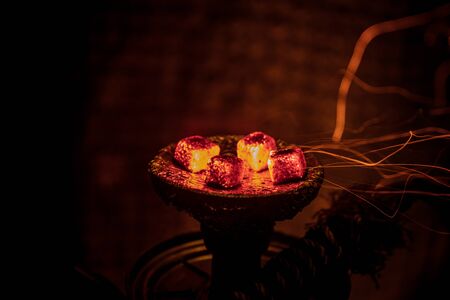 Hookah hot coals on shisha bowl on dark foggy background. Stylish oriental shisha. Creative concept