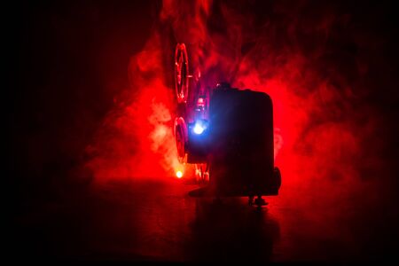 Old vintage movie projector on a dark background with fog and light. Concept of film-making. Selective focusの写真素材