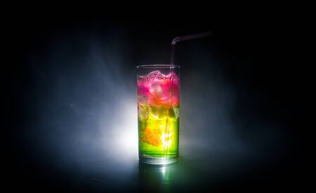 Cocktail glass splashing on dark toned smoky background or colorful cocktail in glass. Party club entertainment. Mixed light. Selective focusの写真素材
