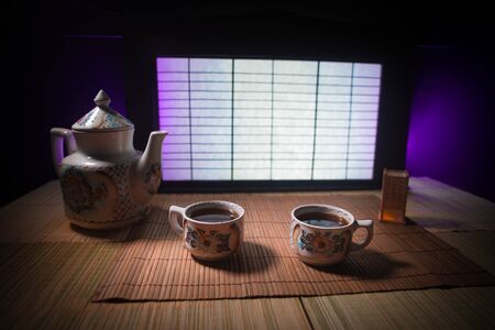 Tea concept. Japanese tea ceremony culture east beverage. Teapot and cups on table with bamboo and tradicional Japan ornament decor elementsの写真素材