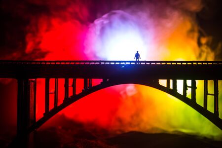 Artwork decoration. Silhouette of powerful metallic bridge at night with foggy backlight. Silhouette of person standing on bridge. Selective focusの写真素材