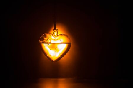 Valentines Day Concept. Beautiful glass heart on dark foggy background. Transparent heart with smoke and glowing lighst on backside. Emptry space for your textの写真素材