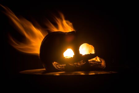 Halloween pumpkin smile and scrary eyes for party night. Close up view of scary Halloween pumpkin with eyes glowing inside at black background. Selective focusの写真素材