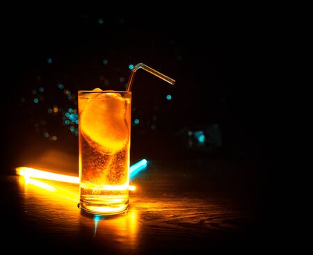 Cocktail glass splashing on dark toned smoky background or colorful cocktail in glass. Party club...