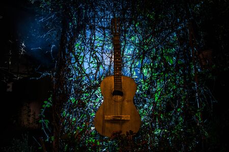 An wooden acoustic guitar at night. with spotlight for your copyspace. old broken guitar