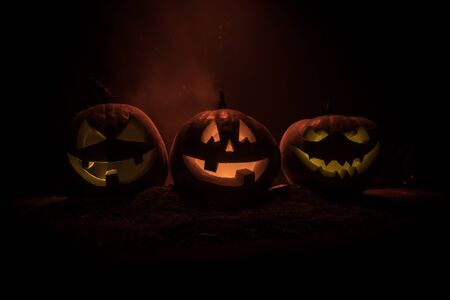 Group of Halloween Jack o Lanterns at night with a rustic dark foggy toned background. Selective focusの写真素材