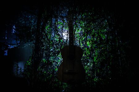 An wooden acoustic guitar at night. with spotlight for your copyspace. old broken guitarの写真素材