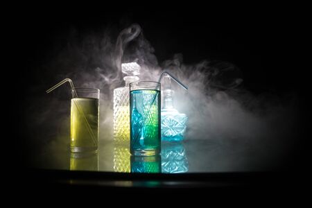 Multicolored glasses filled with alcoholic drinks, with splases of ice cubes falling inside,...