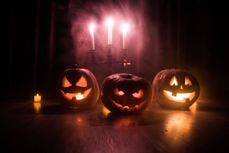 Halloween pumpkin head jack o lantern with glowing candles on background. Pumpkins on wooden floor. Selective focusの写真素材