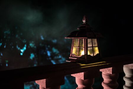 Retro style lantern at night. Beautiful colorful illuminated lamp at the balcony in the garden. Selective focusの写真素材